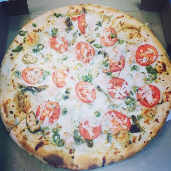 Del Baggio Pizzeria's seafood pizza with shrimp, mussels, tomatoes, and green olives in a box.