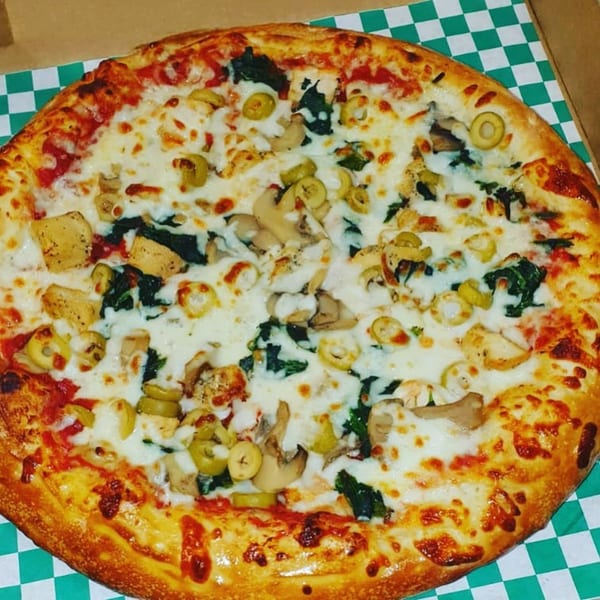 Del Baggio Pizzeria's pizza with white cheese, spinach, mushrooms, and green olives in a box.